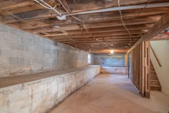 Unfinished block foundation with exposed floor joists and wiring